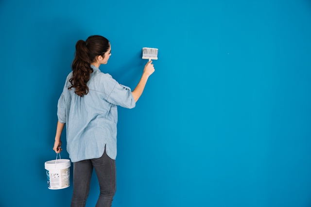 Mulher pintando a parede de azul