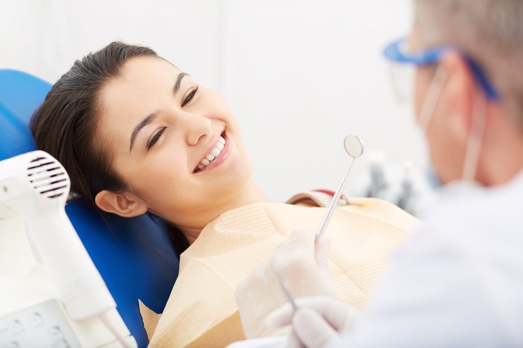 Paciente feliz em atendimento em cadeira odontológica com dentista